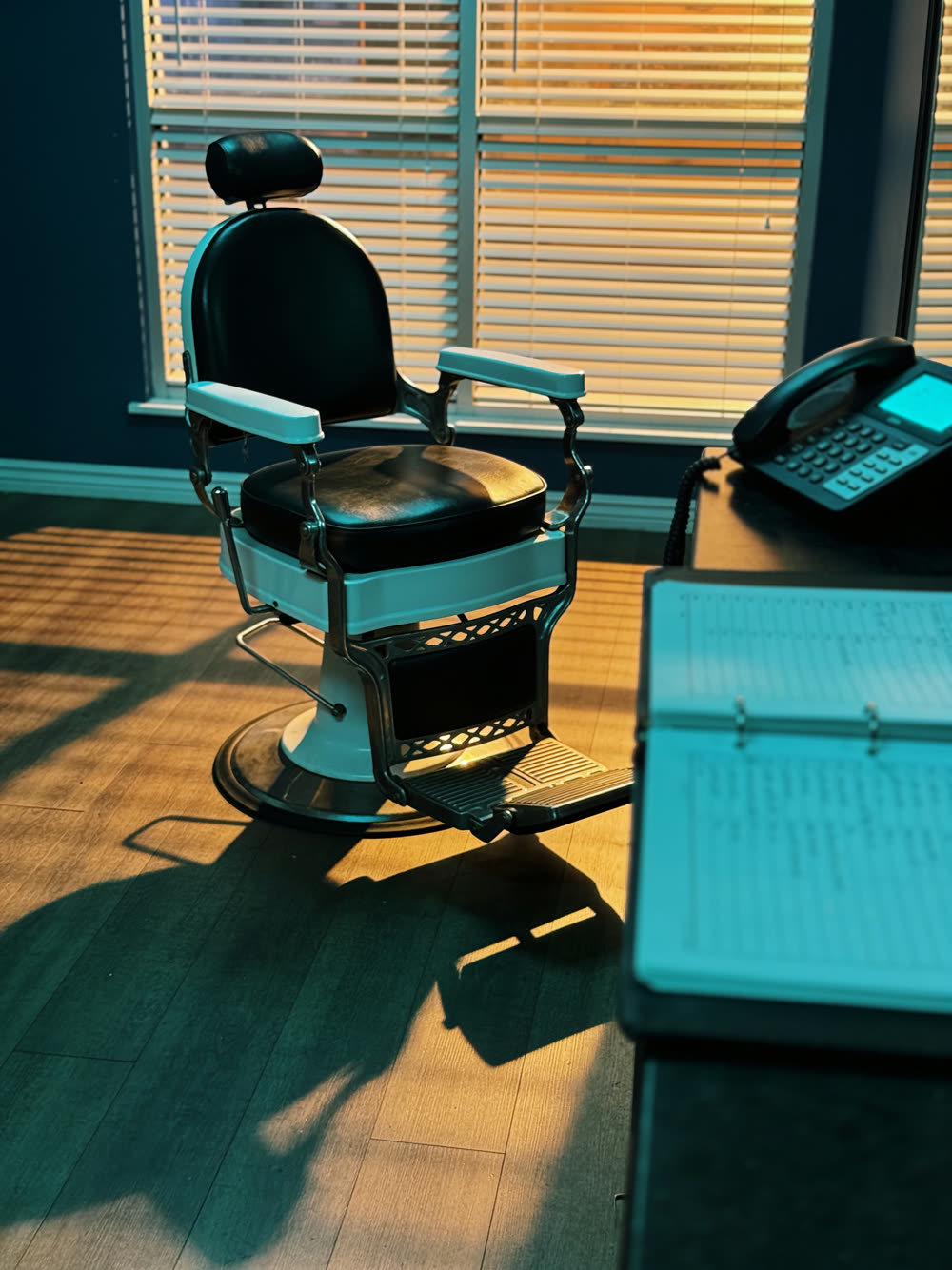 An empty salon chair under warm evening light, appointment book open at the front desk
